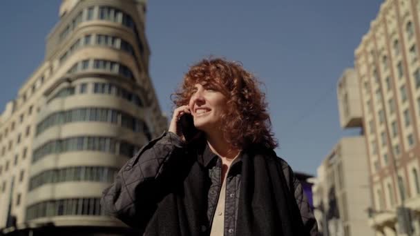 マドリード市内中心部にある美しいカーリーヨーロッパの女性の電話に答える — ストック動画