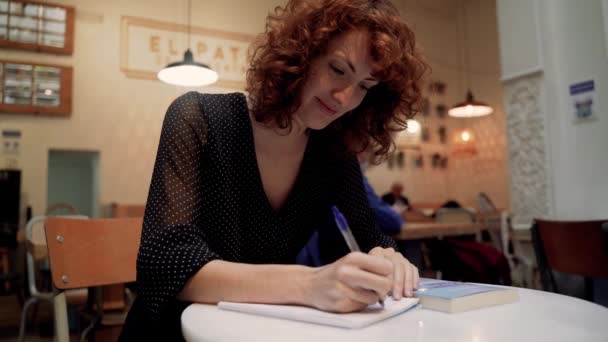 Εμπνευσμένη Νεαρή Σγουρή Φοιτήτρια Κρατώντας Σημειώσεις Στο Δημόσιο Τραπέζι Καφέ — Αρχείο Βίντεο