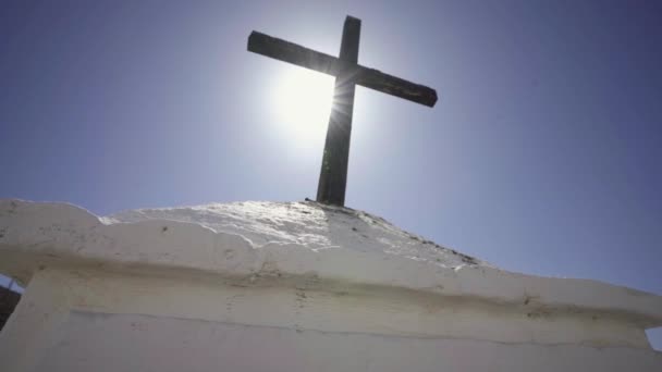 白い石造りの教会の上に澄んだ青い空に太陽の光と信仰と希望の木製のクリスチャンイエス キリストの十字架記号 — ストック動画