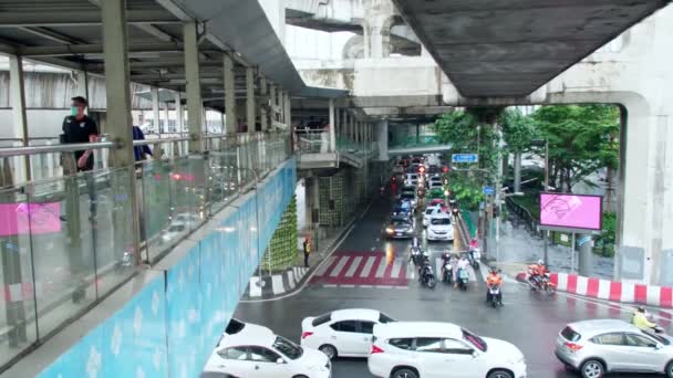 人々はバンコクのラッシュ時に忙しい交差点を介して交通上のスカイウォークを歩く — ストック動画