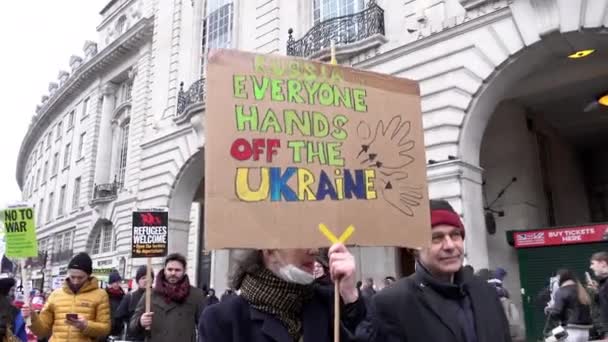 一位妇女手拿着一张色彩艳丽的手工纸板标牌沿着摄政街走着 上面写着 俄罗斯和所有的人都不要碰乌克兰 抗议俄罗斯入侵乌克兰 — 图库视频影像