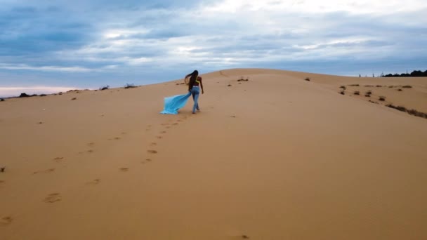Vrouwelijke Wandelingen Langs Rode Zandduinen Met Blauw Materiaal Luchtdrone Volg — Stockvideo