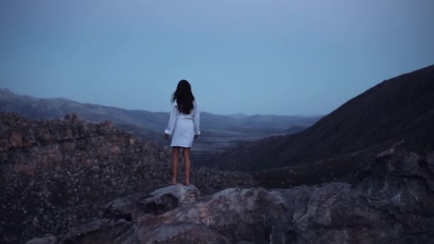 手を上げて崖の上に白いドレスを着た女性 — ストック動画