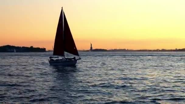 Zeilboot Passeert Voor Het Vrijheidsbeeld Bij Zonsondergang — Stockvideo