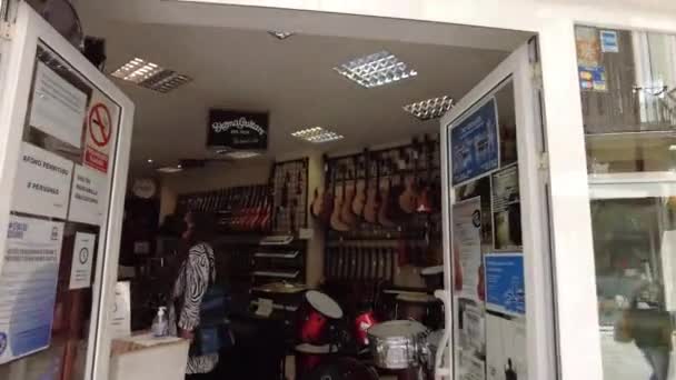 走进马拉加的一家乐器店吉他挂在一家商店的墙上 鼓声在音乐商店里出售 马拉加一家商店里的人供音乐商店出售的乐器 — 图库视频影像