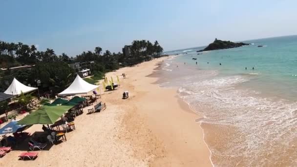 Aerial Dolly People Relaxing Sand Shore Turquoise Sea Surrounded Rainforest — Stockvideo
