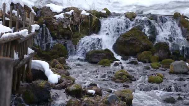 Быстро Текущая Талая Вода Между Большими Скалами Которые Частично Покрыты — стоковое видео