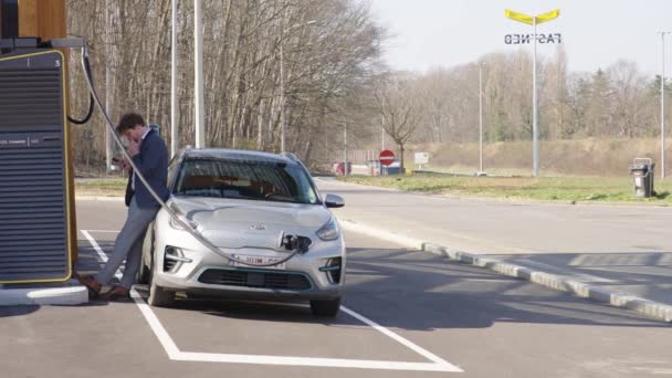 Homme Seul Sur Son Appareil Mobile Penche Contre Voiture Électrique — Video