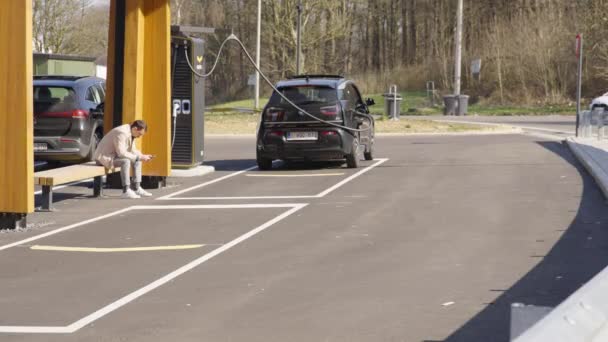 Lone Man Patiently Waits Charging Station His Electric Vehicle Charge — Videoclip de stoc