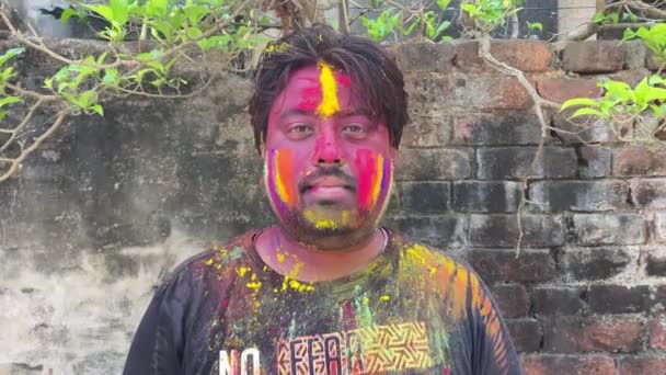インドでホリを祝う男 フルフェイスと笑顔でマルチカラーパウダーで覆われた髪と黒のドレスでインドのひげ男 — ストック動画
