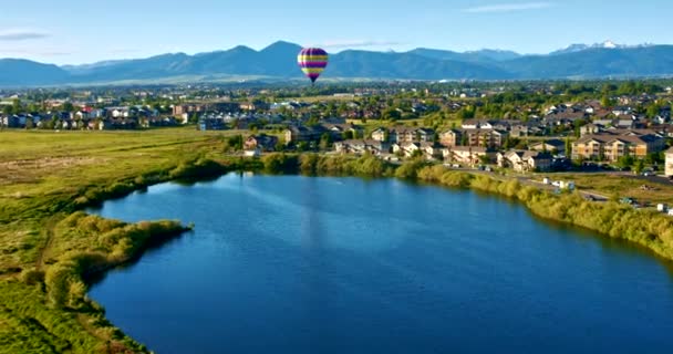 都市の池の上に日の出で熱気球飛行を持つ山 ワイド航空ビュー — ストック動画