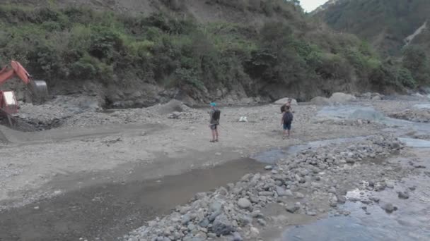 三个人带着重型机械毛虫在石山河床中远足 为建造水泥生产而挖出岩石 中宽空中轨道稳定 — 图库视频影像