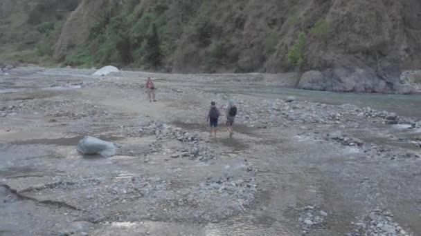 Three Men Hiking Trekking Rocky River Bed Crossing Creek Remote — Vídeo de stock