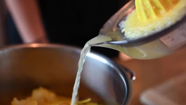 スクイーザーからレモン汁をステンレス鍋に注ぎながら 女性の手の静止ショット スイス ベルン出身のインガーという生姜酒を作っている — ストック動画