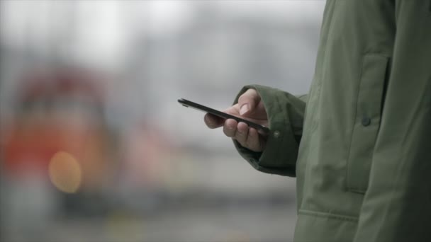 Людина Залізничній Станції Зеленій Куртці Прокручується Через Смартфон — стокове відео