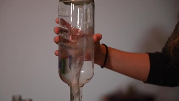 一杯伏特加酒时 一个女人的手被固定地拍了一下 直到最后一滴 她在用圆形的动作摇晃玻璃杯 以制造真空 并迅速地把瓶子清空 — 图库视频影像