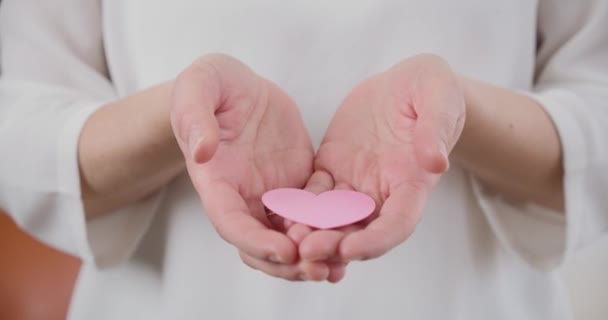 Delicadas Mãos Femininas Oferecendo Coração Papel Rosa Para Câmera Lentamente — Vídeo de Stock