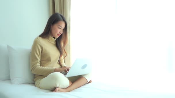 Young Woman Sits Cross Legged Bed Alongside Picture Window Working — Vídeo de Stock