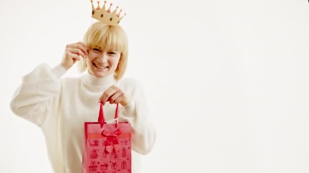 Portrét šťastné ženy baví s falešnou korunou a dárkové tašky izolované na bílém pozadí. Volné místo pro text