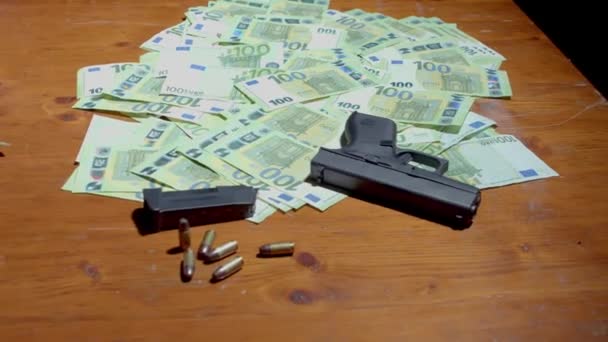Pistole, zásobník, náboje a sto euro na dřevěném stole. - zavřít