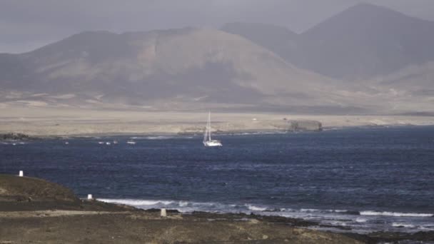 孤独的白帆停泊在西班牙弗尔特文图拉岛金丝雀的海岸线上 海上航行的岛屿突然浮出水面 — 图库视频影像
