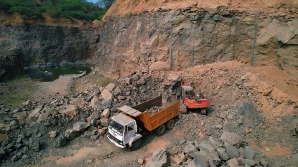 挖掘机的空中俯瞰将矿石和岩石装入货车 露天开采 采矿业概念 将石头装入破碎机的挖掘机的俯视图 — 图库视频影像