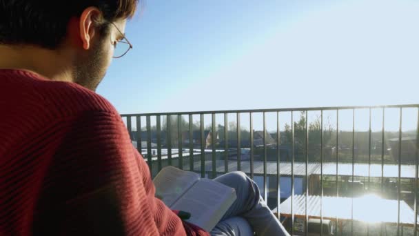 Man Reading Glasses Reading Book His Balcony Sunshine Blowing His — Video Stock