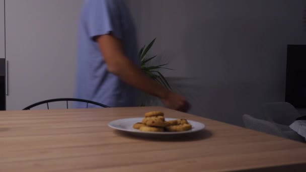 Man Loopt Langs Een Bord Koekjes Eet Allemaal Concept Voor — Stockvideo