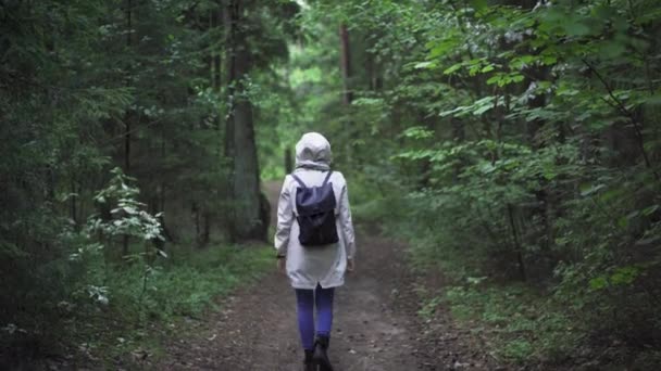 Person Som Går Skogen Klädd Blå Jeans Och Vit Regnrock — Stockvideo
