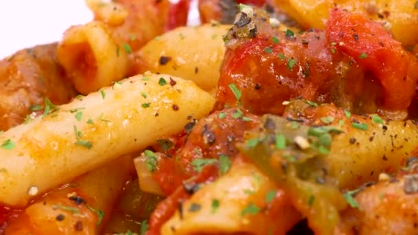 Italské makarony s rajčatovou omáčkou a zeleninou, makrosnímek rotující ve 4k. Zavřít pohled na italské těstoviny na bílém povrchu pozadí.