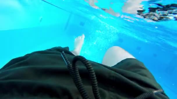 青いモザイクの壁と屋外スイミングプール内の水の男の足の下で 足のパドルハードときに顔を泳ぐ 下のプールの底 濃い緑色のスイミングトランク — ストック動画