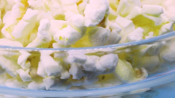 Makro Záběr Popcornu Průhledné Skleněné Misce Rotující Modrém Povrchu Zblízka — Stock video