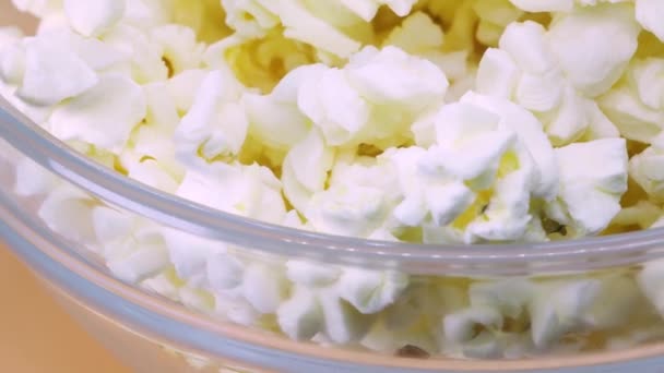 Průhledná Skleněná Mísa Naplněná Popcornem Rotujícím Oranžovém Povrchu Zblízka Makro — Stock video