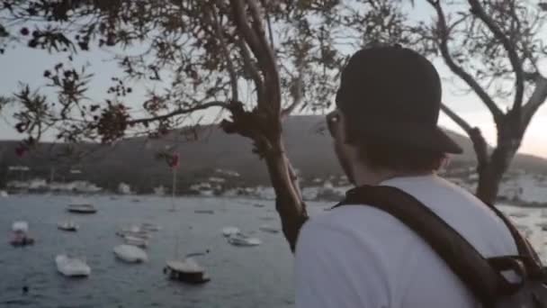 Young Man Traveler Hopping Ledge Sightseeing Ocean Harbor Boats Golden — Stockvideo