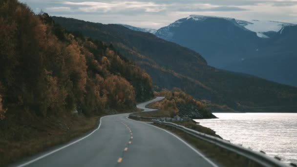 Narrow Two Lane Road Snaking Fjord Snow Capped Mountains Horizon — стоковое видео