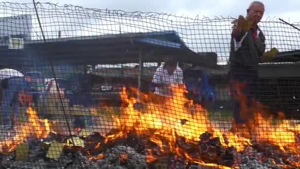 Asian Man Throwing Paper Money Caged Controlled Fire Appease Ancestors — Stock Video