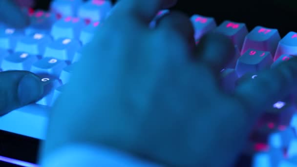 年轻人手拿着铅灯在机械键盘上打字 蓝色和紫色灯火通明的游戏玩家键盘输入4K — 图库视频影像