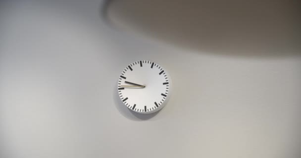 Černobílé hodiny visící na bílé stěně. Akce. Detaily minimalistického interiéru, monochromatické hodiny izolované na bílém pozadí.