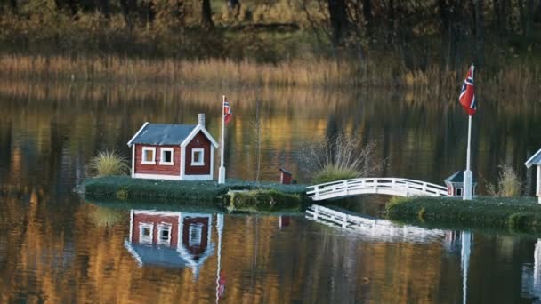在挪威芬恩斯市公园里的一个田园诗般的场景 湖心的玩具屋反映在镜子般的静水中 背景是五彩缤纷的秋叶 慢动作 — 图库视频影像