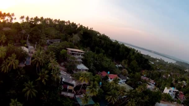 ヒルサイドビーチフロントの空中ドローンパンニングは スリランカの海の上にカラフルな夕日の空と太陽の反射にホテル — ストック動画
