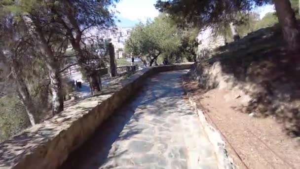 石のタイルで小さな道路でカスティーリョ ジブラルファロから下り坂を歩く マラガ港の美しい景色は以下です 道路の脇に石の壁 景色を楽しむ — ストック動画