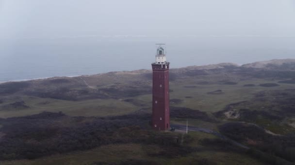 霧に対して緑の風景との間にアウドルップの美しい正方形の歴史的国家記念碑灯台 ニュージーランドの北海包まれた 広いドローンのパンニングショット — ストック動画