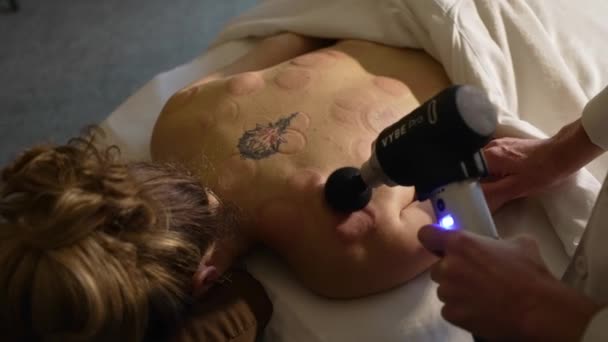 Terapeut Massage Kvinnlig Patient Tillbaka Med Massage Pistol Slow Motion — Stockvideo