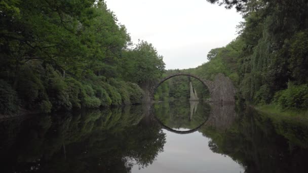 緑豊かなクロムラウ公園の湖の上の神話的な石のアーチ橋 — ストック動画