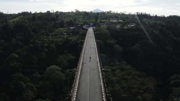 Aerial Male Jogging Wilderness Running Concrete Suspension Bridge Crossing Green — Video