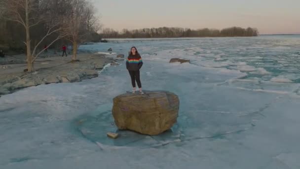 Young Women Wearing Pride Colors Jacket Rock Middle Frozen Lake — Stock Video