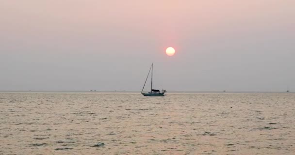 太陽との素晴らしい夕日タイのパタヤ近郊のバンサレーにあるシルエットのヨットで地平線を越えて行きます 4Kで静止中ズームショット — ストック動画