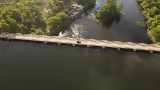 阿根廷落日时分 一辆黑色轿车在河上桥坝上行驶的空中跟踪拍摄 4K南美荒野中的汽车旅行 — 图库视频影像