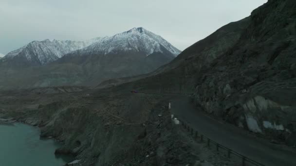 コーチと雪に覆われた山々を背景に旅するハンザ渓谷の山岳道路の空中円ドリービュー — ストック動画