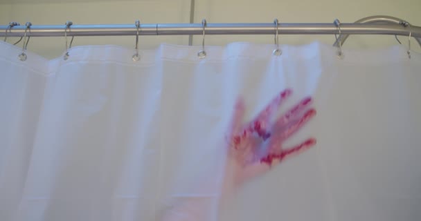 Medium shot of a bloody hand grabbing a shower curtain and sliding down, leaving bloody streaks behind.